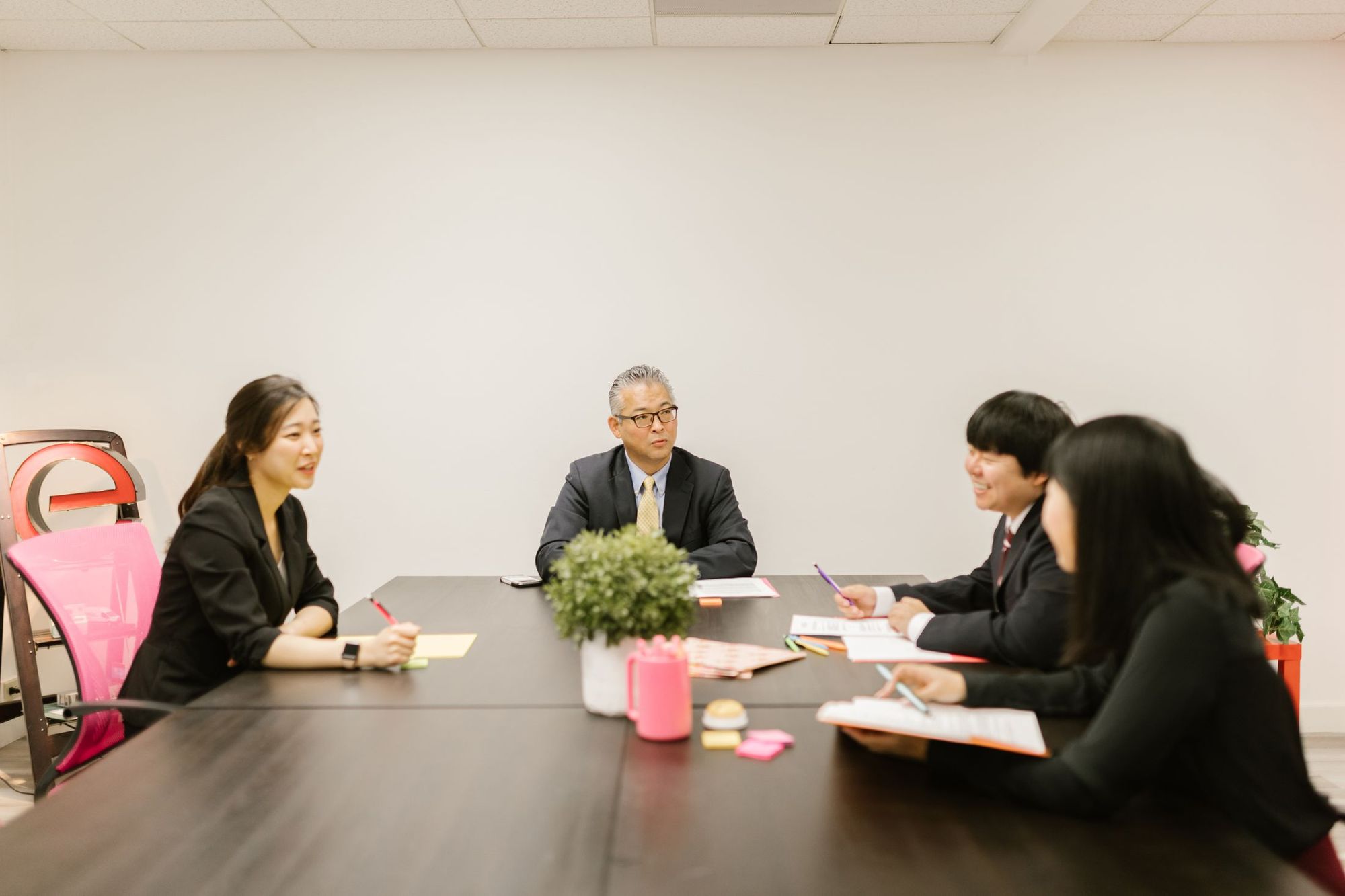 会議室のテーブルを囲んで話し合う人たち