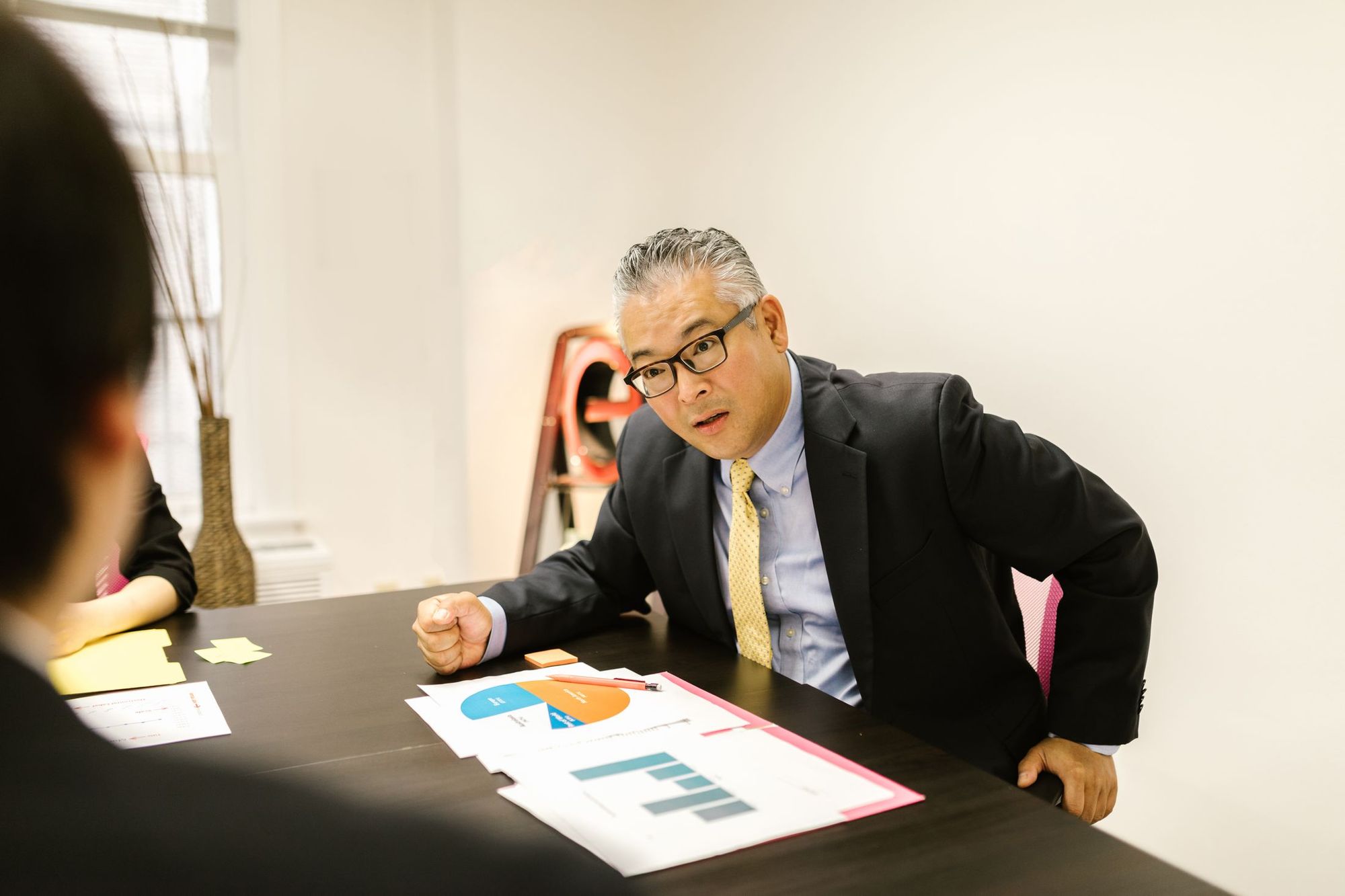 グラフを印刷した資料を前に話す人